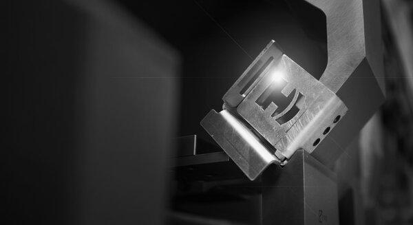 Sheet metal part with the HACO logo cut out, held in a press brake
