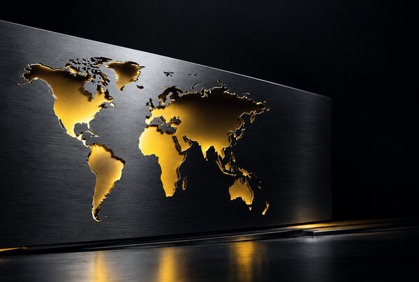 World map cut out of brushed steel, lit in gold